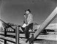 Photograph: [Reporter Layne Beaty sitting on a fence]