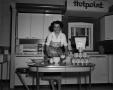 Photograph: [Margaret McDonald poses on kitchen set]