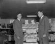 Photograph: [Two men standing in front of Frito display in store]