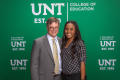 Photograph: [Two attendees standing in front of UNT backdrop]
