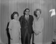 Photograph: [Two women and a man in front of curtain]