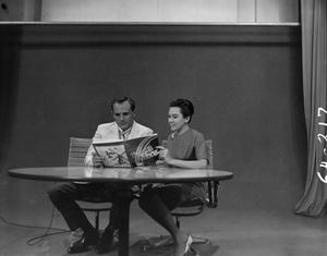 Primary view of object titled '[Bobbie Wygant and guest looking at magazine]'.