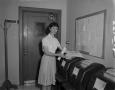 Photograph: [Woman receiving wire machine prints]
