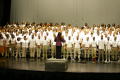 Photograph: [Choir members standing on stage together]