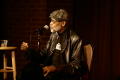 Photograph: [Photograph of Melvin Van Peebles in a chair on stage at a film festi…