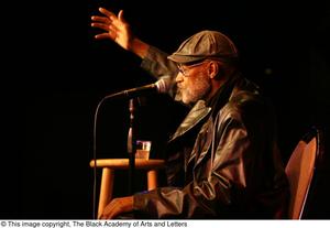 Primary view of object titled '[Photograph of director Melvin Van Peebles seated on stage at a film festival]'.