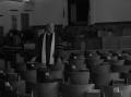 Photograph: [Reverend J. D. Mooring standing in Church hall]