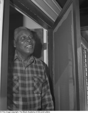 Fotografía en blanco y negro de Earley Collins de pie en una puerta.