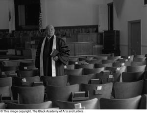 Primary view of object titled '[Reverend J. D. Mooring standing in Church hall, 2]'.