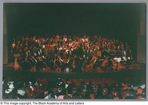Primary view of object titled '[Photograph of an orchestra ensemble and choir on a stage]'.