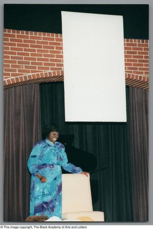 Primary view of object titled '[Photograph of Mzuri with her hand on a chair]'.