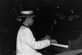 Photograph: [Right angled medium shot of an unidentified man playing the piano]