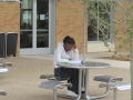 Primary view of [Student at table outside of Business Leadership Building]