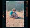 Photograph: [Photograph of a Pam Williams sitting in a yard]