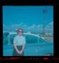 Photograph: [Photograph of a woman standing outside a blue automobile]