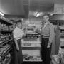 Photograph: [Man and woman in front of display at Eddlemon's Food Shop]
