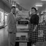 Photograph: [Man and woman standing in front of Cook Book Cakes display 1 of 2]