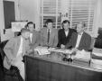 Photograph: [Photograph of men seated at desk]