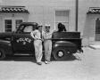 Photograph: [Photograph of men leaning on a police truck]