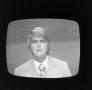 Photograph: [Journalist appearing on a television screen]