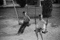 Photograph: [Photograph of Tim Williams and a friend on a swing set]
