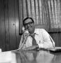 Photograph: [Photograph of Ron Godbey speaking on a telephone]