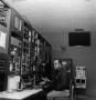 Photograph: [Unknown man sitting at a control panel]