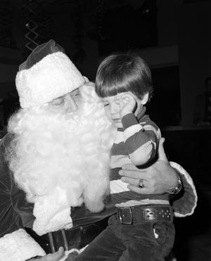 Primary view of object titled '[Photograph of Santa holding a young boy at a KXAS Christmas Children's Hour party]'.