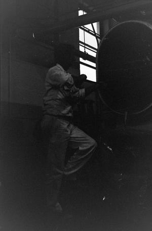 Primary view of object titled '[Photo of man working with engine]'.