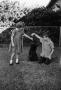 Photograph: [Pam and Byrd Williams IV playing with dog, Angus, in a yard]