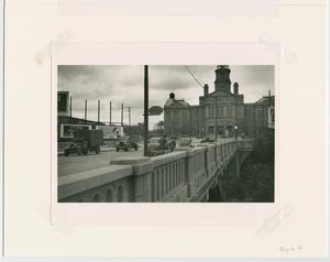 Foto en blanco y negro de un puente de la autopista, con un edificio al fondo.