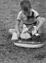 Photograph: [Photograph of Tim Williams playing with a toy boat]
