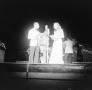 Photograph: [Photograph of individuals gathered behind a microphone on stage, 3]