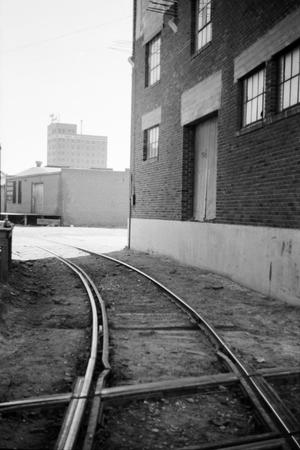 Primary view of object titled '[Photograph of train tracks running near a building, 2]'.