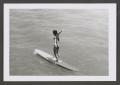 Photograph: [Photograph of a woman standing on a surfboard]