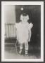 Primary view of [Photograph of a little girl standing next to a chair]