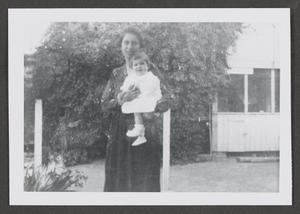 Primary view of object titled '[Photograph of a woman holding a baby outside]'.