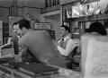 Photograph: [Men behind a shop counter]