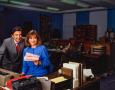 Photograph: [Photograph of Jane McGarry and a man standing at a desk]