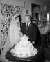 Photograph: [A bride and groom with their wedding cake]