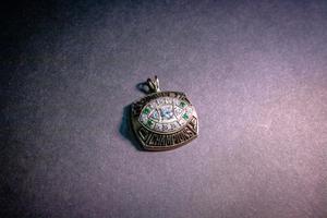 A silver pendant with crystals on it in the shape of a football. It is not attached to anything.