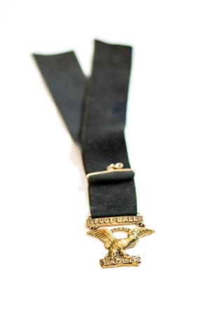 Black lanyard with a gold pendant in the shape of an eagle. At its feet is the word Eagles, and above it the word Football.
