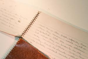 Un cuaderno de notas abierto y rasgado, que se muestra con escritura a mano.