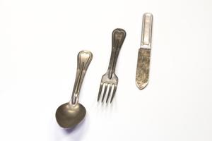 Silver spoon, fork and knife beside each other.