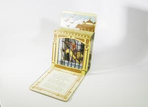 A book opened up to the pop-up, one page laying flat and the pop-up part standing up. The pop-up is of a woman with a lion jumping behind a caged cell, sticking out like a box. Above the boxed pop-up is an illustration of the sky and the top of a building partially seen.