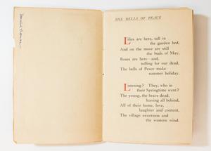 A booklet open, the page on the left blank and the page on the right containing a poem titled The Bells of Peace at the top of the page.