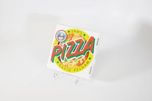 Portada de un libro que se asemeja a una caja de pizza blanca. El diseño de la caja es una piza de pepperoni con un borde amarillo, la palabra Pizza sobre ella en grandes letras rojas y verdes. En la esquina superior derecha hay una ilustración circular de un niño.