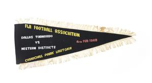 A black flag fringed by white thread. It says Fiji Footbal on it in yellow letters, Dallas Tornado in white letters.