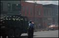 Photograph: [Military Driving Down a Street]