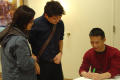 Photograph: [B. D. Wong signing papers for guests]